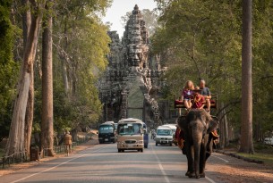 Tourists ride on the back of an elephant on Thailand street.