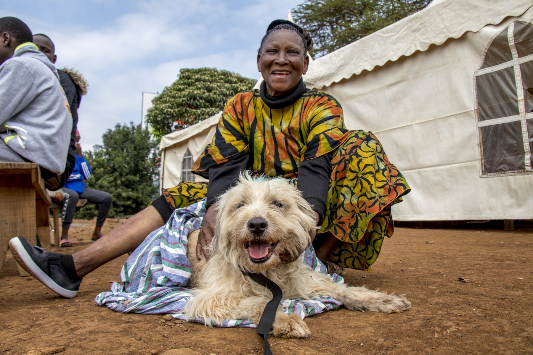 Dog sitting with its owner at rabies vaccination drive in Kenya - World Animal Protection